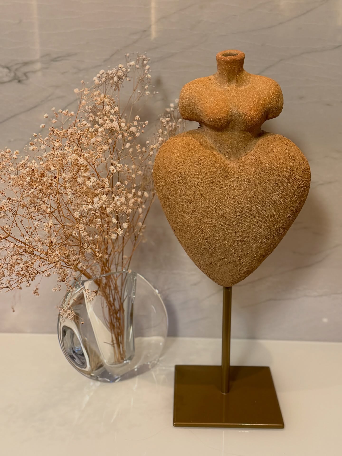 Escultura simbólica que une um torso feminino e a forma de um coração