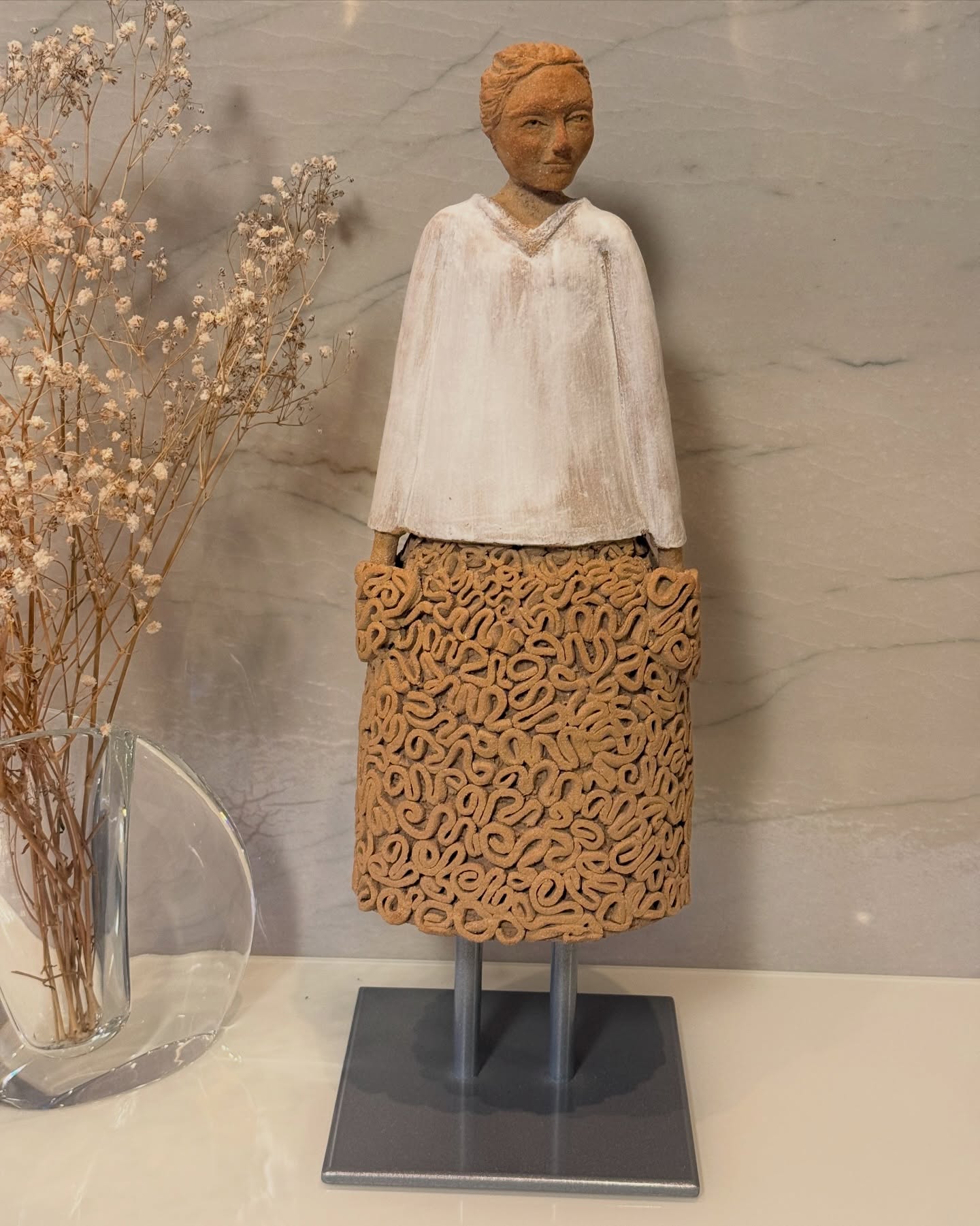 Escultura policromada de uma figura com saia rendada