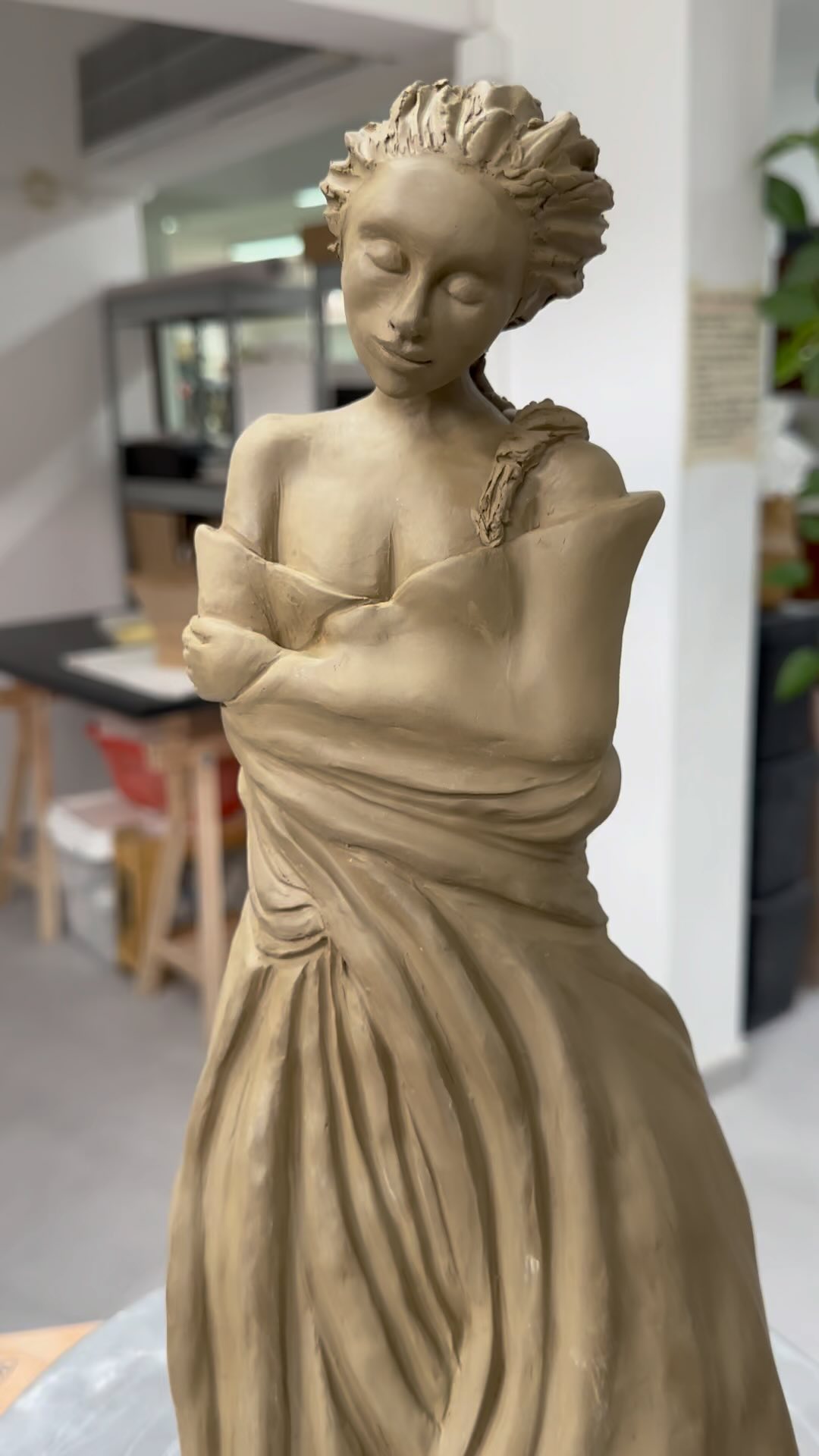 Escultura monocromática de uma figura feminina com um livro